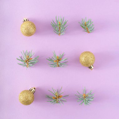 Kış tatili kompozisyonu. Noel altın madalyaları, mor arka planda köknar dalları.