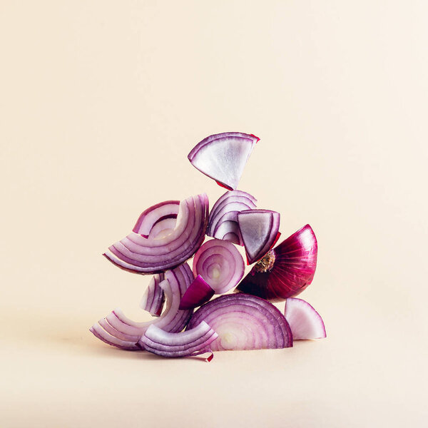 Creative composition of sliced red onion on earthy beige background. Equilibrium floating food balance.