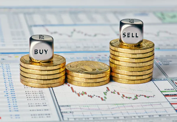 Οικονομική γράφημα, νομίσματα και ζάρια κύβους με τις λέξεις που πωλούν αγορά. s Εικόνα Αρχείου