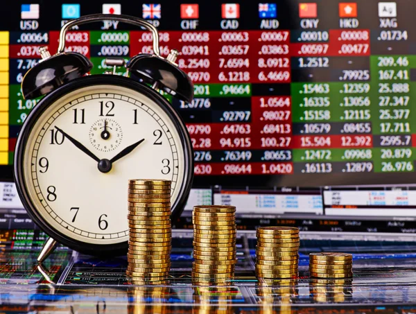 Columnas de tendencia a la baja de monedas de oro con un reloj despertador. Financi —  Fotos de Stock