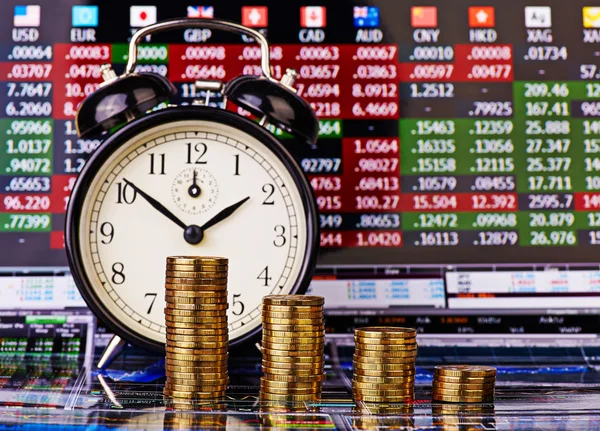 A downtrend stacks of golden coins with an alarm clock. Financia — Stock Photo, Image