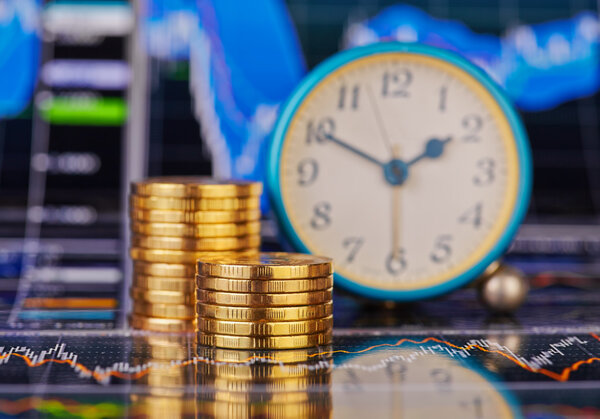 Пачки золотых монет, часы и финансовый график
