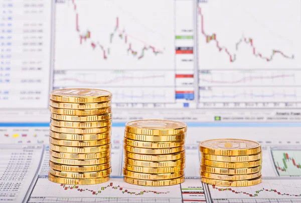 Down trend stacks of golden coins and financial chart as the bac — Stock Photo, Image