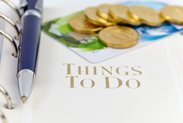 Cartão de crédito, moedas de ouro e caneta esferográfica na página de um organiz — Fotografia de Stock