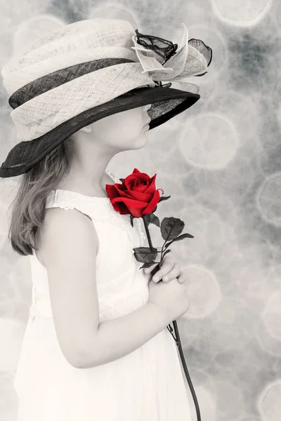 Little girl holding a red rose — Stockfoto