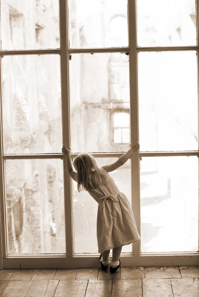 Chica joven mirando por una ventana — Foto de Stock