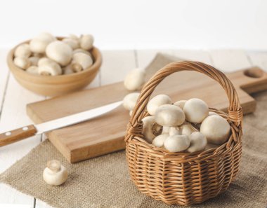 a plate and a basket of mushrooms with a knife on a chopping board close-up.