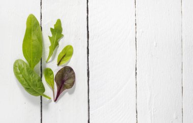 lettuce leaves with spinach, chard and arugula on a white background of boards. A flat surface with a copy of the space.