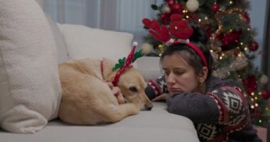 Hüzünlü, yalnız bir genç kadın, Noel 'de boynuzlarını takmış, evinde, koltuğun yanında hayal kırıklığına uğramış bir şekilde oturuyor.