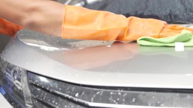 Profesyonel bir işçi, profesyonel oto yıkama istasyonunda mikrofiber bezle araba yıkayıp cilalıyor..