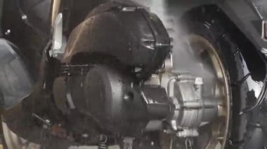 Temizlik için hortum kullanan profesyonel bir işçi. Profesyonel oto yıkama istasyonunda motosiklet yıkamak ve spreylemek..