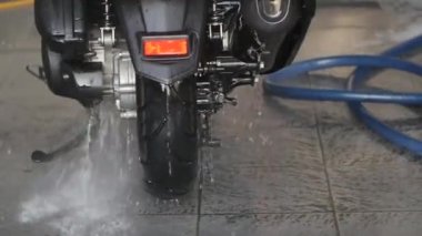 Temizlik için hortum kullanan profesyonel bir işçi. Profesyonel oto yıkama istasyonunda motosiklet yıkamak ve spreylemek..