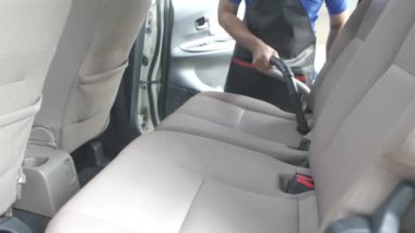 Arabada elektrikli süpürge kullanan profesyonel işçilere yakın çekim. Servis istasyonunda araçları süpüren adam