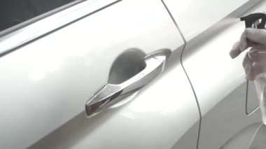 Arabanın dışını temizlemek ve dezenfeksiyon sıvısı sıkmak. Eller plastik koruyucu eldivende vihicles kapı kolunu dezenfekte ederek virüs hastalığına karşı korunuyor.