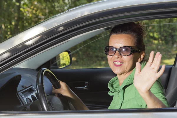 Cute woman in the car waving hello — Stock Photo, Image