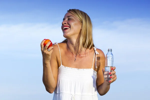 Mladá žena s lahví a ovocem — Stock fotografie