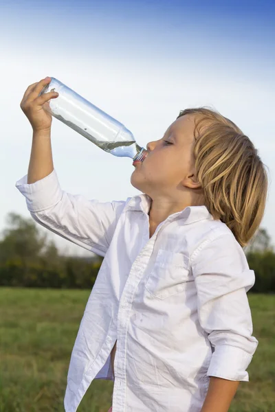 Young boy drinking water outdoors Stock Picture