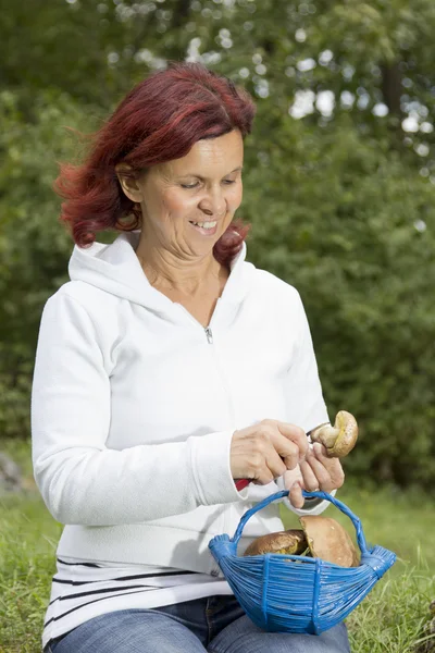 Niedliche Frau, die Steinpilze putzt — Stockfoto