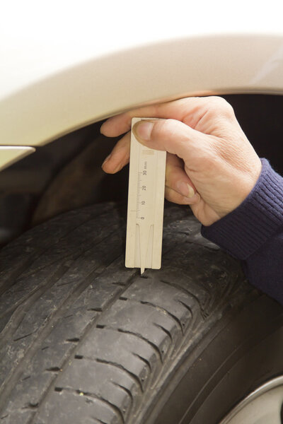 Женщина-водитель измеряет профиль шины
