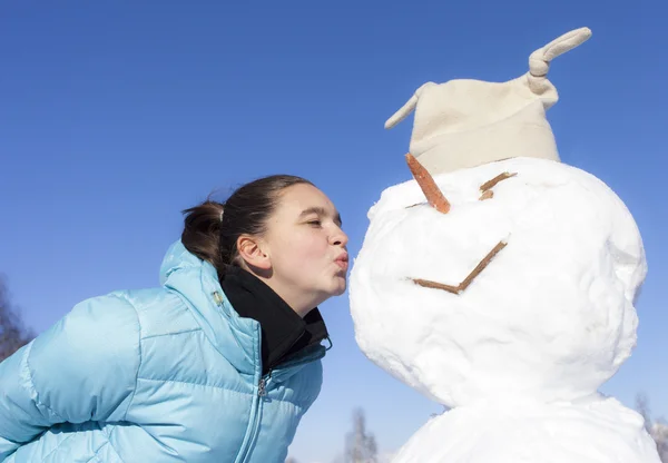 Fille mignonne embrasser le bonhomme de neige — Photo