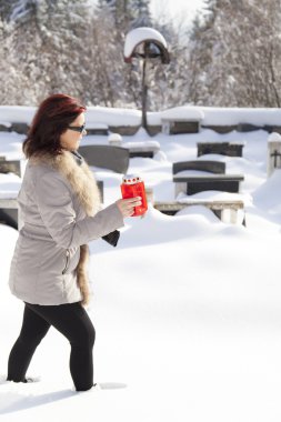 Mid aged woman with candle on snowy cemetery clipart