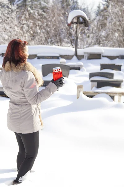 Mid aged woman with candle on snowy cemetery — Stock Photo, Image