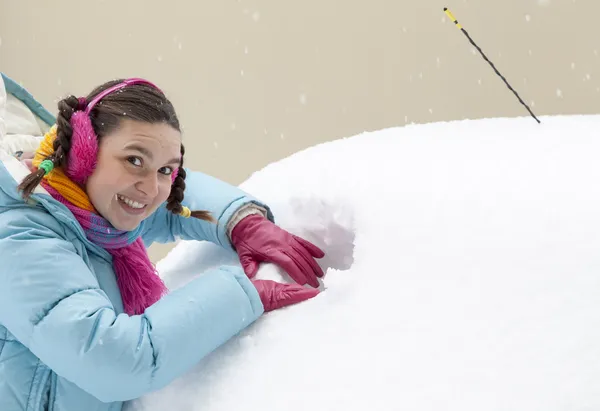 Carino donna driver fare un buco in un finestrino auto innevata — Foto Stock