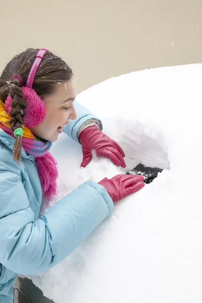 Mujer linda conductor haciendo un agujero en una ventana de coche nevado — Foto de Stock