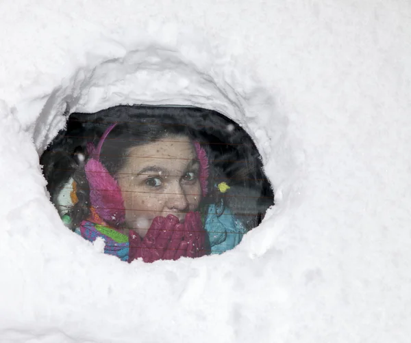 Мила жінка водій дивиться з-за сніжного вікна автомобіля — стокове фото