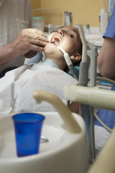 Девушке с зубной болью врач проверяет зубы — стоковое фото