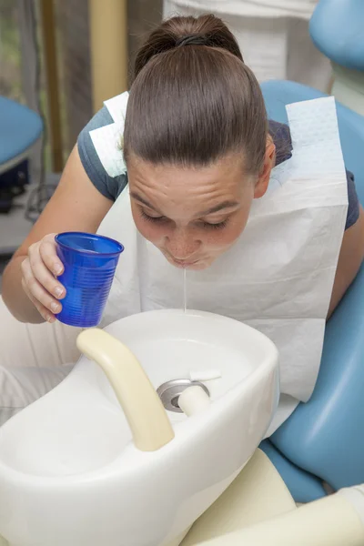 Cute girl rinsing mouth after having her teeth checked by doctor — Stock Photo, Image