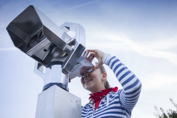 Mladá usměvavá žena pomocí mince, dalekohled — Stock fotografie