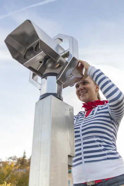 Joven mujer sonriente usando prismáticos operados con monedas —  Fotos de Stock