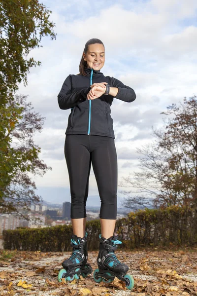 Chica patinadora comprobando el tiempo y el pulso — Foto de Stock