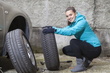 Young smiling woman driver replacing tires clipart