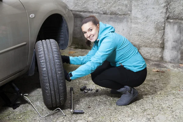 Menina bonita substituindo pneu de carro Fotos De Bancos De Imagens
