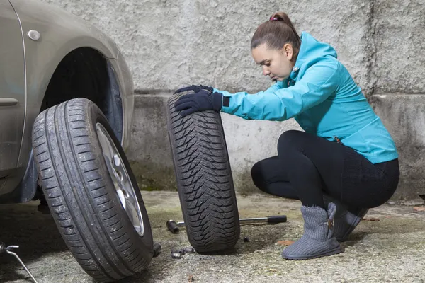 Menina bonita substituindo pneu de carro Imagem De Stock