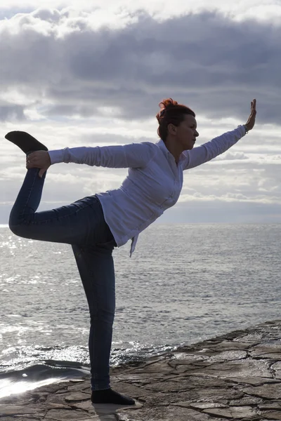 Mujer de mediana edad en la playa realizando Yoga —  Fotos de Stock