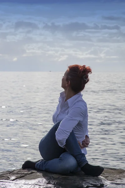 Женщина средних лет на берегу моря, занимающаяся йогой — стоковое фото
