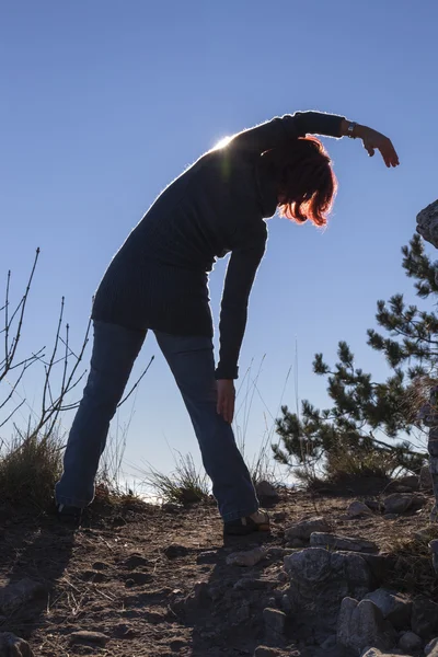 Yoga ile güneşin arkasında gerçekleştiren bir kadın silueti — Stok fotoğraf