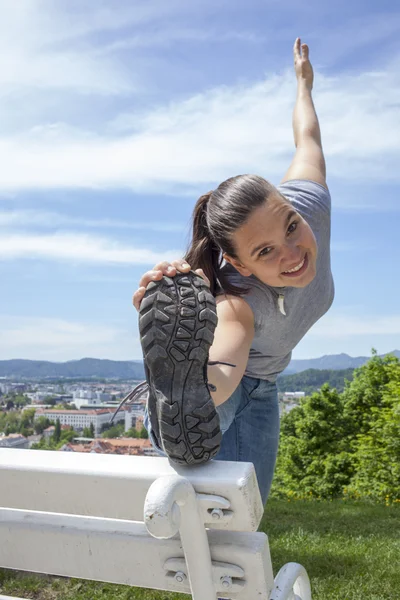 Sportig unga kvinnan sträcker benet utomhus — Stockfoto