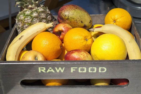 Frutas orgânicas frescas em caixa de madeira, texto RAW FOOD — Fotografia de Stock