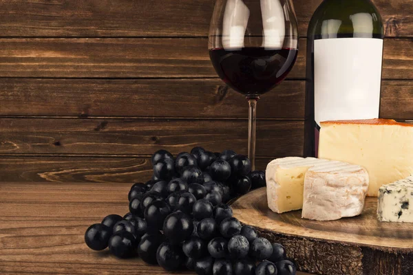 Bottle and glass of wine isolated on a wooden plank in the background. Blank label and copy space for your text.