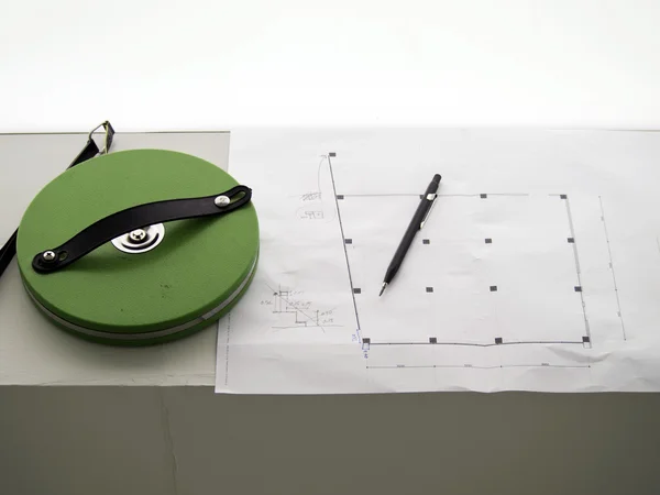 Measuring tape and a pencil over a construction drawing — Stock Photo, Image