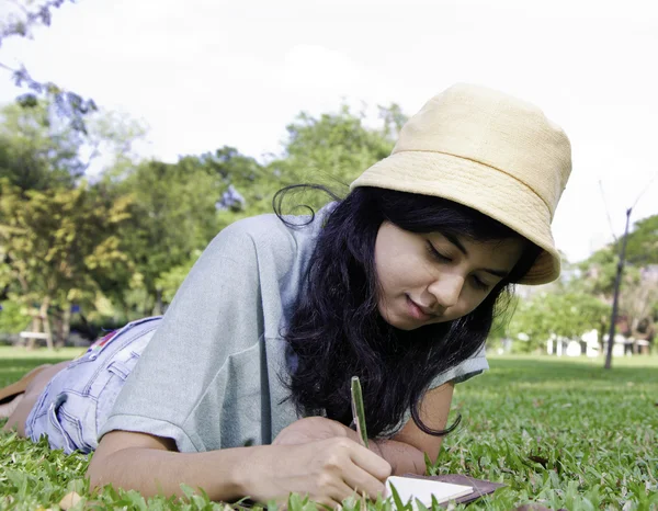 Jeune fille asiatique écrit un livre — Photo