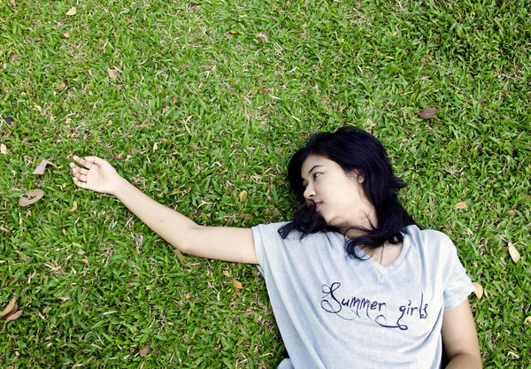 Aziatische vrouw in het gras te leggen — Stockfoto