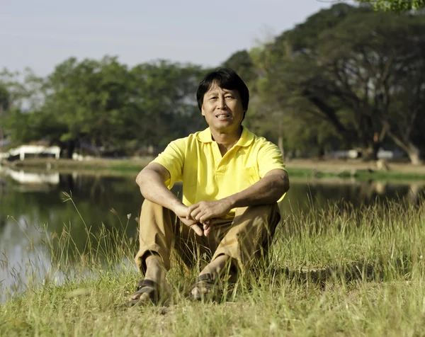 Aziatische man zit in het park — Stockfoto