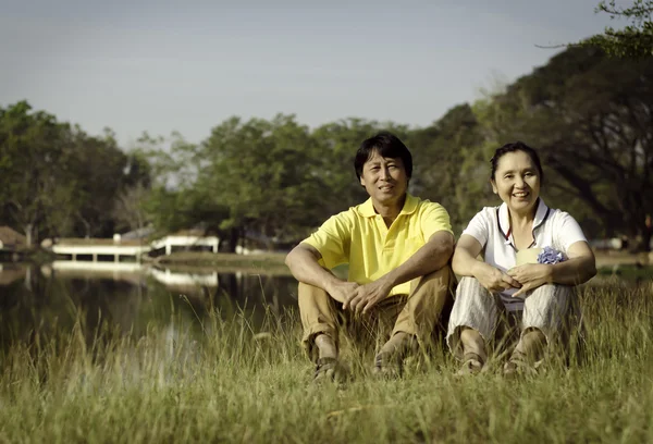 Portrait of beautiful couple sitting on ground in park — Stock Photo, Image