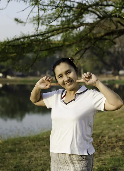 Glad asiatisk kvinna poserar mot bakgrund av träd — Stockfoto