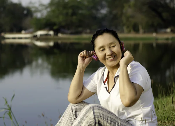 Mooie Aziatische vrouw luisteren muziek in hoofdtelefoon met gesloten — Stockfoto